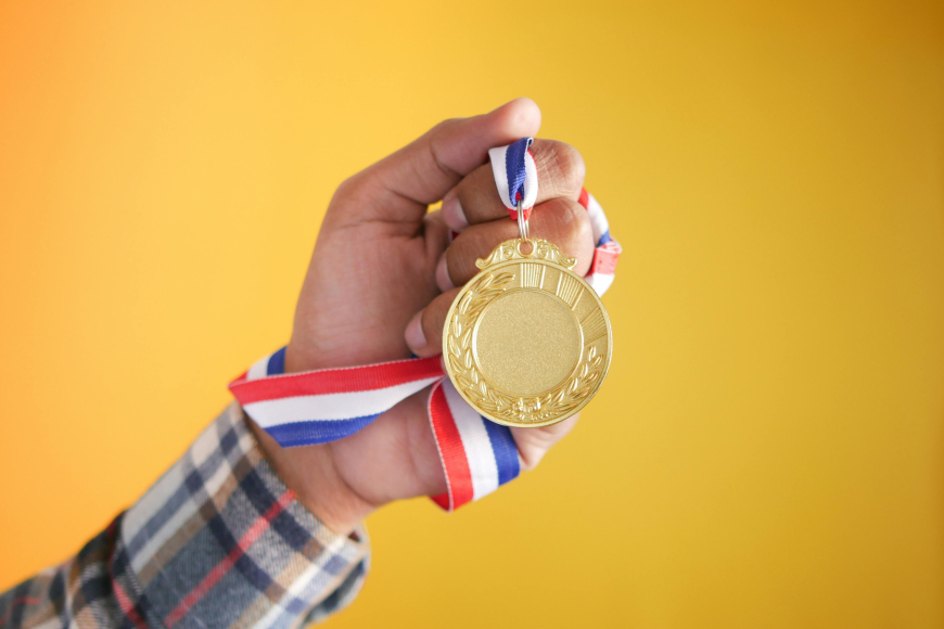 osoba u ruci drži zlatnu medalju